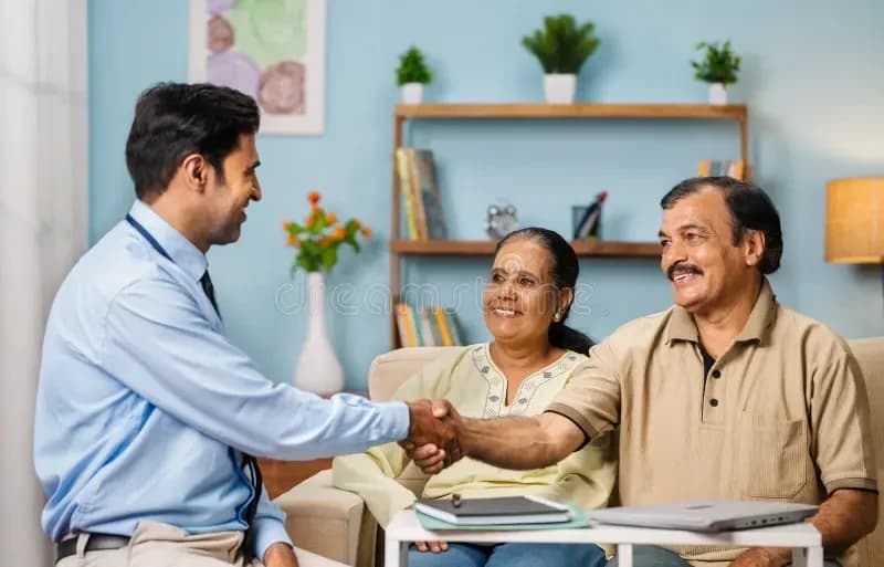 An advisor shaking hands with an Indian couple at home after reviewing their plan